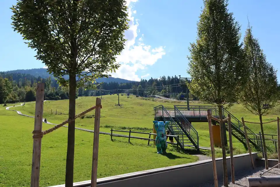 Ende der Rodelrinne am Blomberg mit jungen Bäumen, dahinter die Talstation des Sessellifts