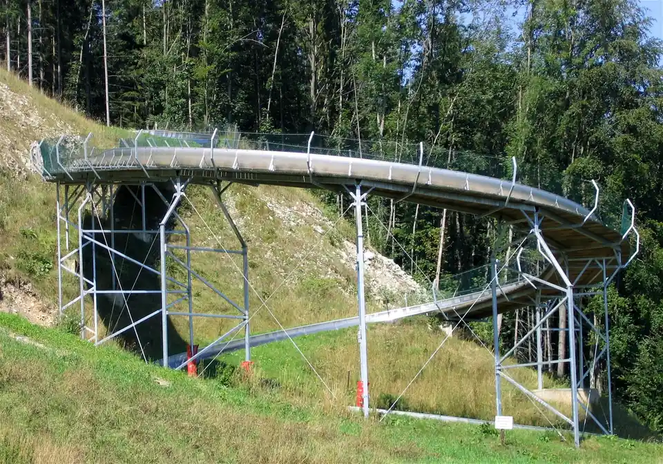 Rodelrinne in einer erhöhten Kreiskurve auf einem Stahlgerüst am Waldhang