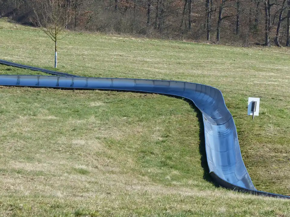 Nahaufnahme einer Kurve der Edelstahlrinne, die sich durch eine Wiese zieht