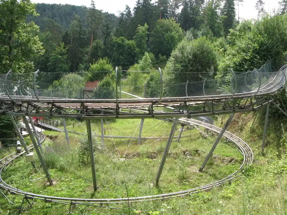 Schienenbahn läuft in einer Spirale auf schrägen Stahlstützen durch eine Waldwiese