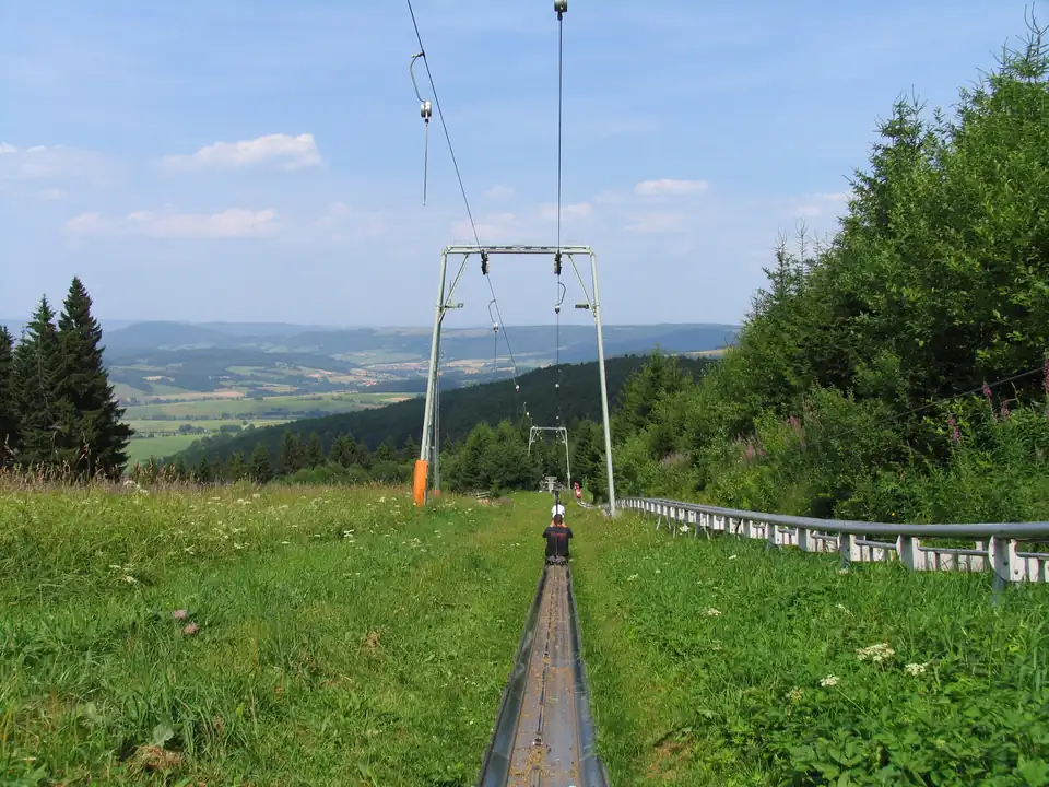 Gerade Rodelrinne mit dem Zugseil des Aufzugs, Blick über die Hügel der Rhön